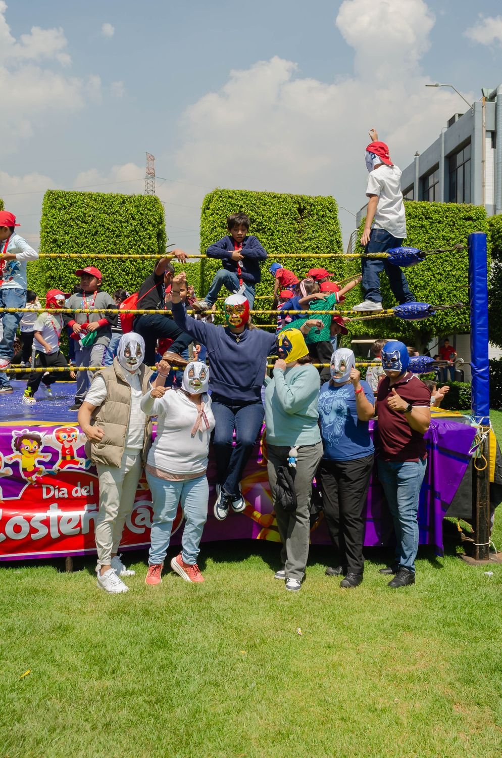 Grupo de adultos con máscaras de luchador frente al ring del Día del Costeño