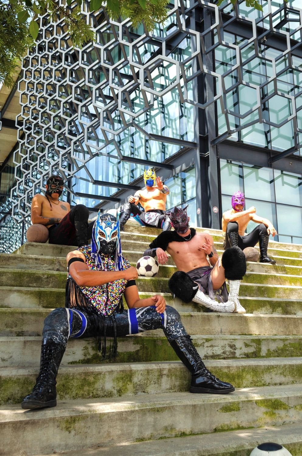 Cinco luchadores enmascarados posando en unas escaleras