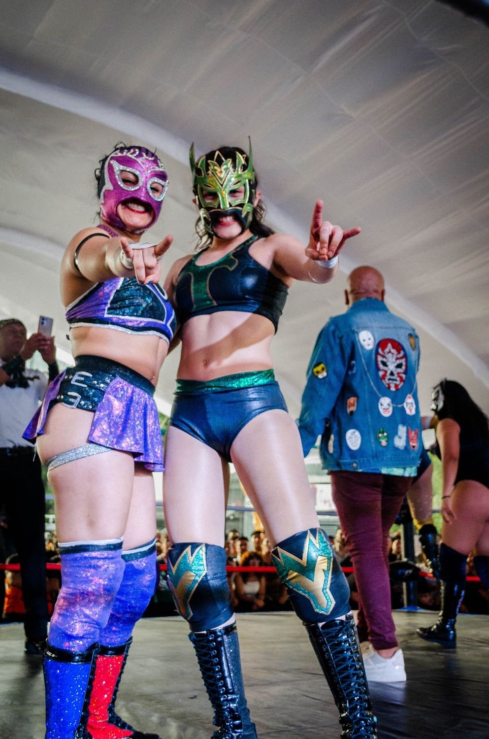 Dos luchadoras con máscara señalando a la cámara sobre el ring